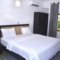 a bedroom with a large bed with white sheets at Hôtel La Couronne RW, Yaoundé