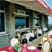 a restaurant with tables and chairs on a deck at Logis Hotel Du Casino, Vierville-sur-Mer