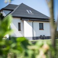 a white house with a black roof and some grass at Domek u Mai, Zator