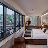 a bedroom with a large bed and large windows at Hotel President Sarajevo