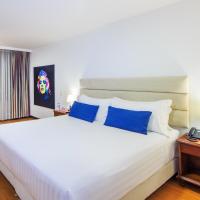 a bedroom with a large white bed with blue pillows at Pop Art Hotel Manizales Centro Histórico