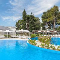 a pool at a hotel with white chairs and umbrellas at Amadria Park Beach Hotel Jakov, Šibenik
