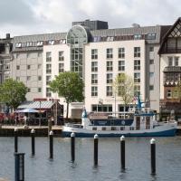 a boat in the water in front of a building at Ramada by Wyndham Flensburg