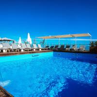 a swimming pool with chairs and the ocean in the background at Capsis Astoria Heraklion