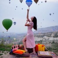 a young girl in a pink dress holding up balloons at Kayatas Cave Suites, Göreme