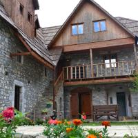a stone house with a balcony and flowers at Shpella Guesthouse Theth