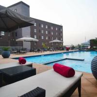 a swimming pool with chairs and a vase with a plant at Oak Plaza Suites, Kumasi