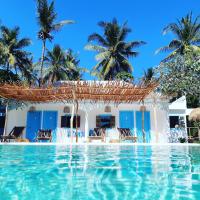 a swimming pool in front of a house with palm trees at The Koho Air Hotel, Gili Islands
