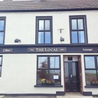 a white building with a sign that reads the local at The Local Lodge, Longford