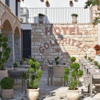 a stone wall with tables and chairs and plants at Hotel Goloritzé, Baunei