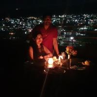 a man and a woman standing on a balcony at night at Woodland Hill Stay, Shillong
