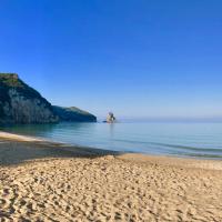 a sandy beach with a rock in the water at Sebastian's - Agios Gordios Beach
