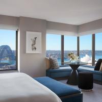 a hotel room with a bed and a couch and windows at Four Seasons Hotel Sydney
