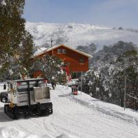 a truck driving down a snow covered road in front of a house at Summit Ridge Alpine Lodge, Falls Creek