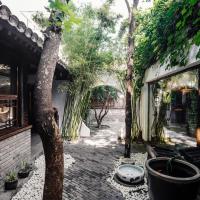 a courtyard with a tree and some potted plants at The Orchid Hotel - Old Town & Drum Tower, Beijing
