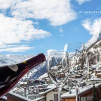 a bottle of wine and two wine glasses at Hotel Ambassador Zermatt