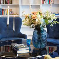 a blue vase with flowers on a table with books at Hotell Vesterhavet, Falkenberg