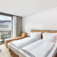 a bedroom with two beds and a large window at H2 Hotel Leipzig