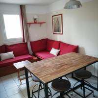a living room with a red couch and a wooden table at LES GRANDS PINS, Carcans