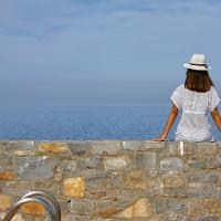 a woman sitting on a wall looking at the ocean at Vasia Resort & Spa, Sisi