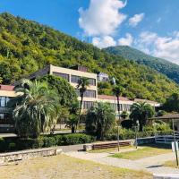 a building with palm trees in front of a mountain at Hotel Continent Gagra