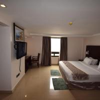 a hotel room with a bed and a television at Noble House Hotel, Kumasi