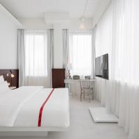 a white bedroom with a bed and a desk at Ruby Leni Hotel Dusseldorf, Düsseldorf
