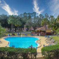 a swimming pool at a resort with chairs and trees at APM Inn & Suites - Jacksonville