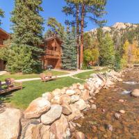 a log home with a river and a stone wall at Woodlands on Fall River, Estes Park