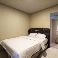 a bedroom with a bed with a black headboard and a sink at RedDoorz near Taman Merdeka Metro Lampung