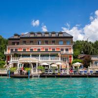 a hotel on the water next to a body of water at Seehotel Porcia, Pörtschach am Wörthersee