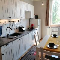 a kitchen with white cabinets and a table and a sink at Panoráma apartman, Tapolca