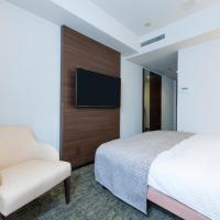 a bedroom with a bed and a chair and a tv at HOTEL MYSTAYS Fukuoka Tenjin