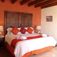 a bedroom with a large bed with orange walls at Casa del Tio Hotel Boutique, San Miguel de Allende