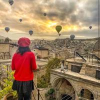 a woman standing on a balcony looking at hot air balloons at Aydinli Cave Hotel, Göreme