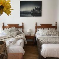 a bedroom with two beds and a vase with a flower at Apartamentos Arha, Potes