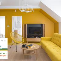 a living room with a yellow couch and a tv at Colors Apartments Zator - tylko 10 minut piechotą od Energylandii
