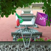 two flags are flying in front of a pink building at Mercure Bergamo Centro Palazzo Dolci