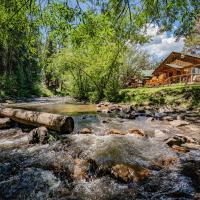 a river with a log in front of a house at Colorado Bear Creek Cabins, Evergreen