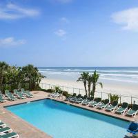 a swimming pool with lounge chairs and the beach at Days Inn by Wyndham Daytona Oceanfront, Daytona Beach
