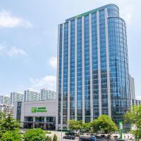 a tall glass building in a city with buildings at Holiday Inn Qingdao City Center, an IHG Hotel - Shopping MALL