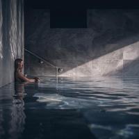 a man in a pool of water with a rod at Le Parc Hôtel Obernai & Yonaguni Spa