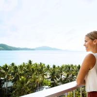 a woman standing on a balcony looking out at the water at Reef View Hotel, Hamilton Island