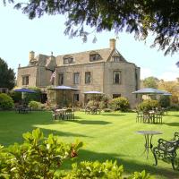 a large house with tables and chairs in the yard at Stow Lodge Hotel, Stow on the Wold