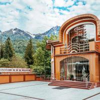 a building with a balcony with mountains in the background at Alm House, Krasnaya Polyana