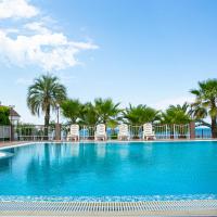 a large swimming pool with chairs and palm trees at Alex Resort & Spa Hotel, Gagra