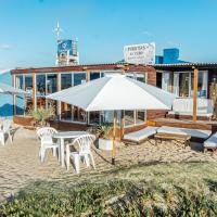 a beach with chairs and umbrellas and a building at Puertas al Cabo, Cabo Polonio