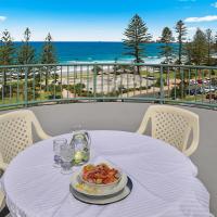a table with a plate of food on a balcony with the beach at Alex Seaside Resort, Alexandra Headland