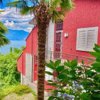 a red building with a palm tree in front of it at Appartamento Buresso, Porto Valtravaglia