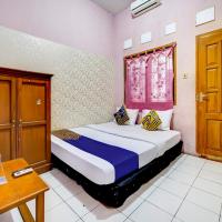 a bedroom with a bed and a table and a window at SPOT ON 90171 Pondok Kuning, Sayang
